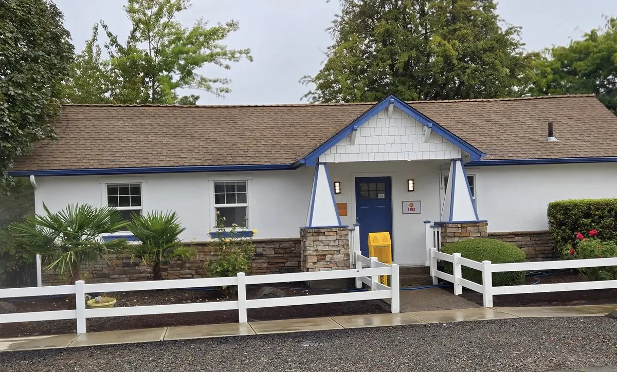 White commercial building with blue trim and a wet walkway after an exterior wash