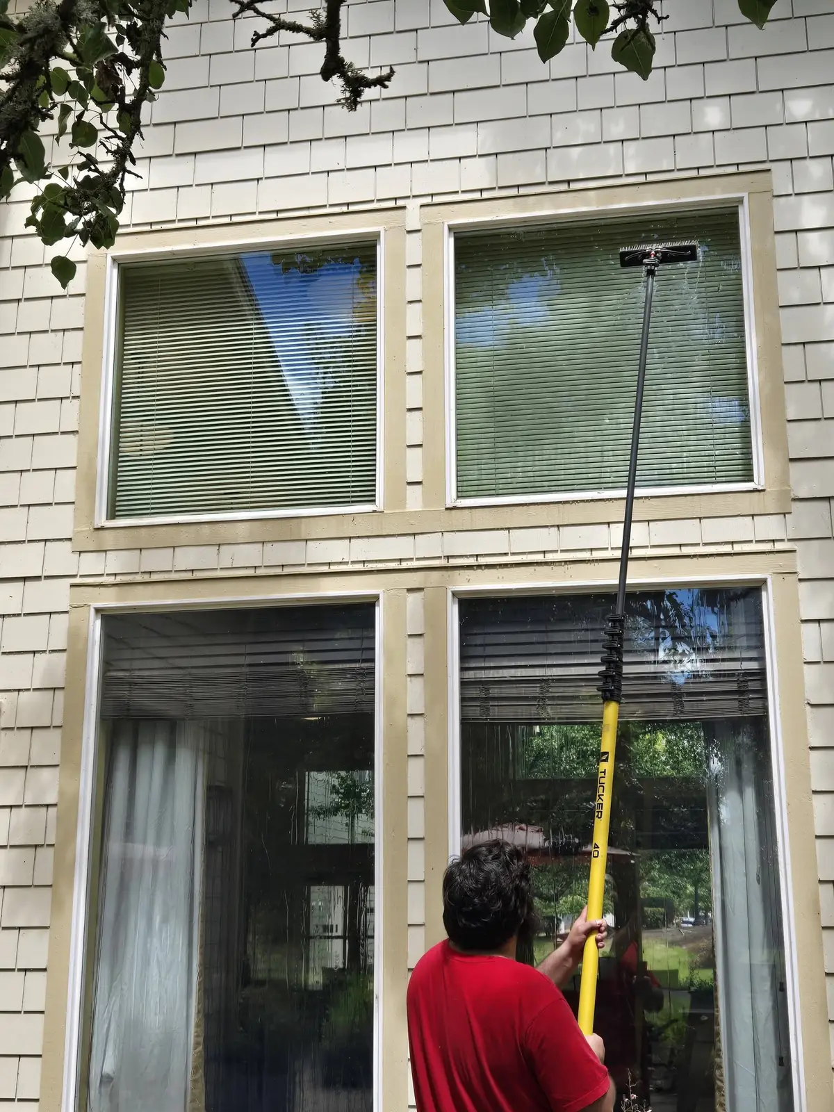 Technician using a water-fed pole to clean second story windows